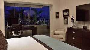 Ein Schlafzimmer mit einem großen Bett, einem Schreibtisch, einem Stuhl, einer Kommode und einem Fernseher.