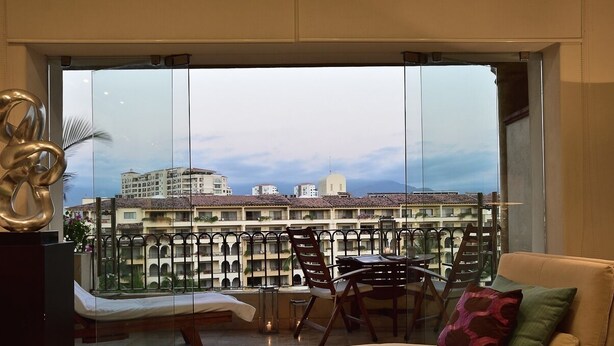 Ein Balkon mit Blick auf ein Hotelgebäude, einer Couch und einem Tisch mit Stühlen.