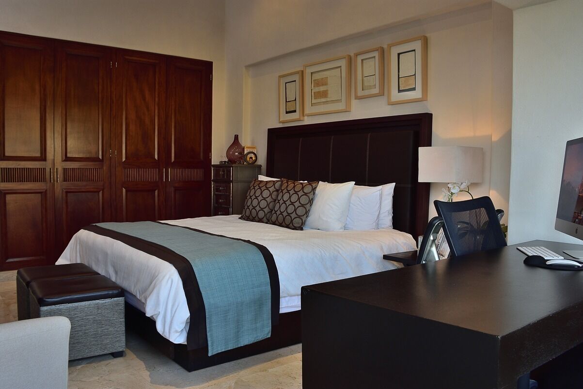 A hotel room with a large bed, a desk with a computer, and a wardrobe.
