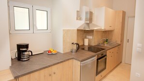A modern kitchen with a built-in oven, a coffee maker, and a fruit bowl. - Galielo Boutique Suite by Corfuescapes  (Corfu)