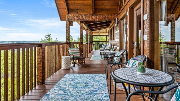 Una terraza de madera con mobiliario exterior, incluyendo sillas y una mesa, con vistas a un paisaje pintoresco.
