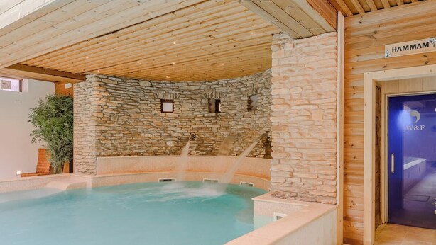 Una piscina interior con paredes de piedra y vigas de madera.