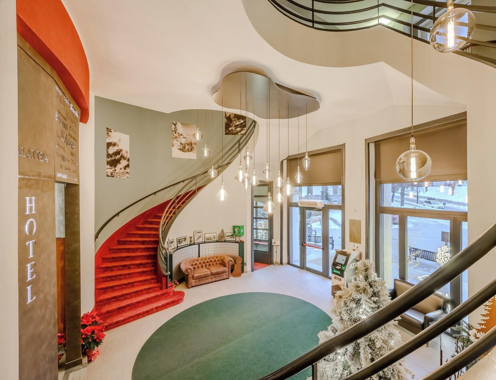 Un'accogliente hall d'albergo con una scalinata a chiocciola, una reception e un albero di Natale.