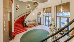 A hotel lobby with a spiral staircase, a reception desk, and a Christmas tree. - Hotiday Sauze Torre (Sauze d'Oulx)