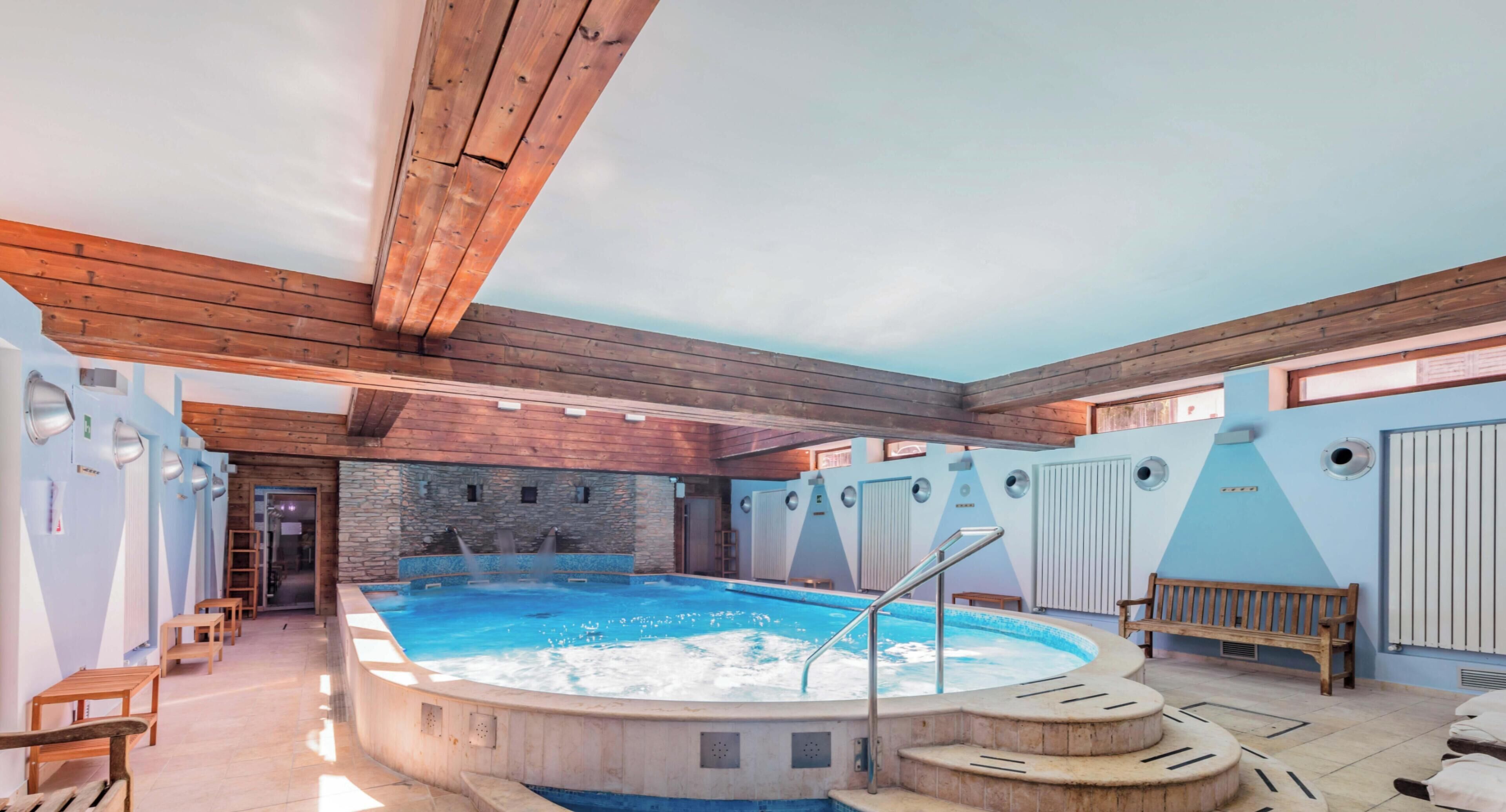Un espace de détente avec un jacuzzi, des bancs en bois et un mur en pierre.