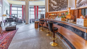A bar area with a piano, bar stools, and a large window with red curtains. - Hotiday Sauze Torre (Sauze d'Oulx)