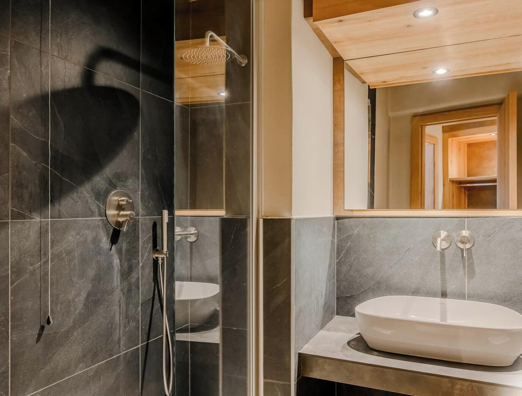 A modern bathroom with a glass-enclosed shower, a white sink, and a wooden ceiling.