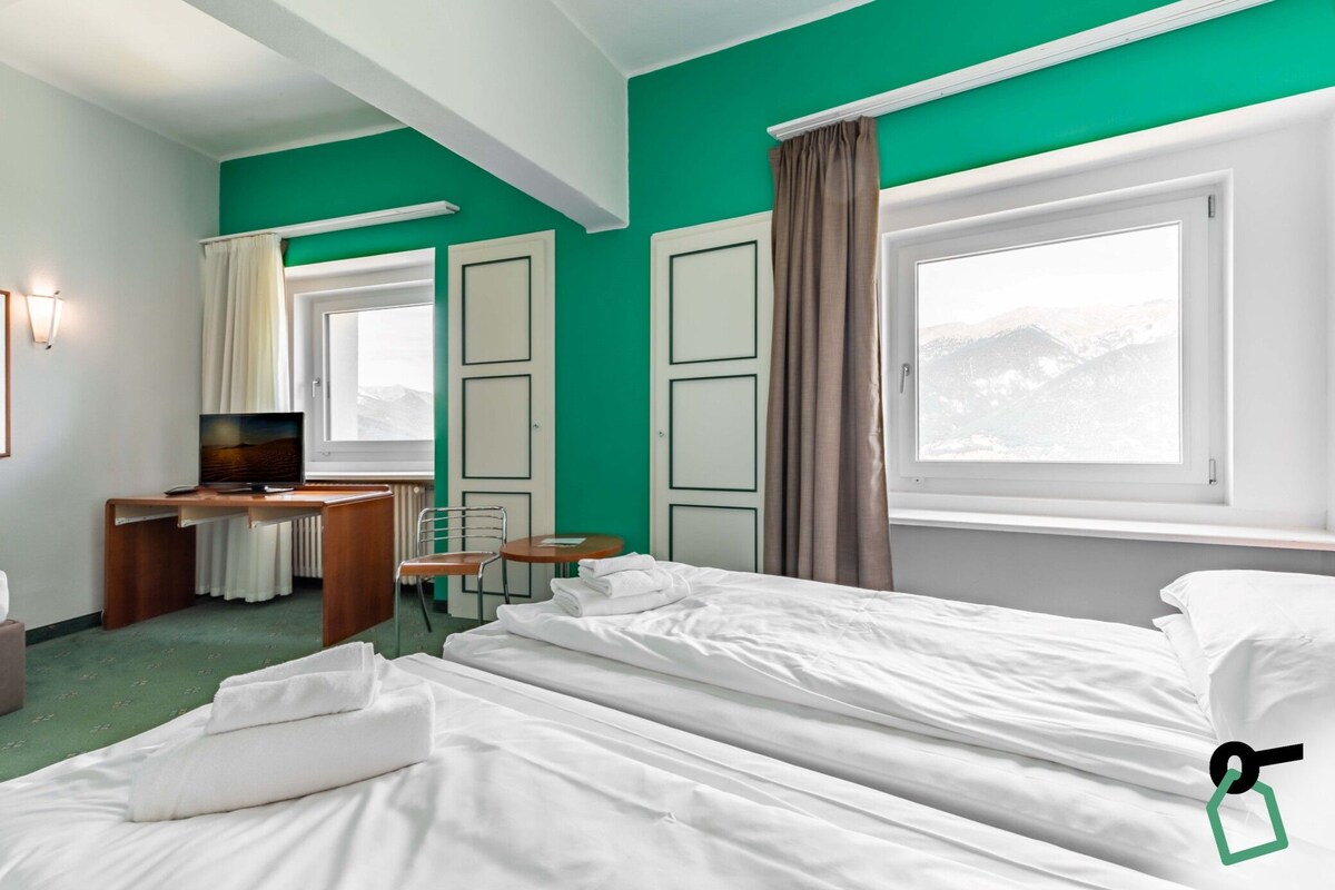 Una habitación de hotel con una cama, un escritorio, una silla y un televisor.