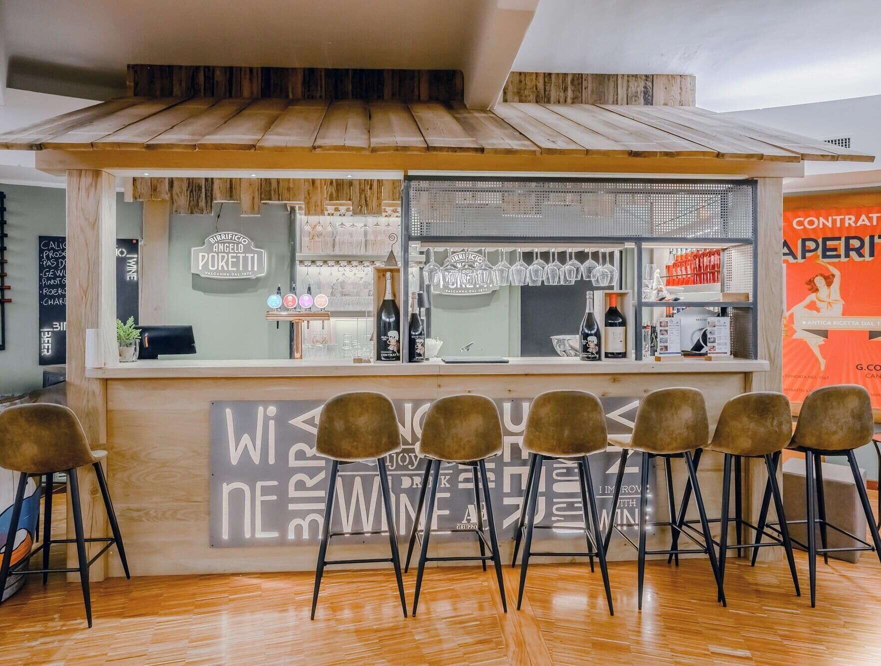 A bar area with a counter, bar stools, and a menu board.