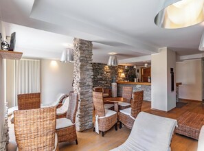 Un salón amplio con muebles de mimbre, una pared de acento de piedra y una cocina al fondo.