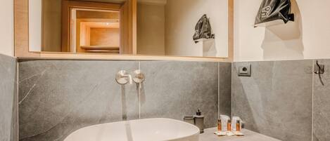 Un baño moderno con una bañera independiente, un espejo y un perchero para toallas.