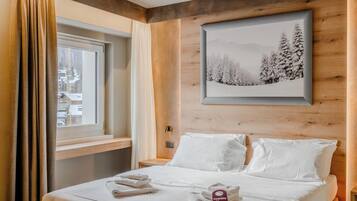 A hotel room with a bed, a window with curtains, a framed picture on the wall, and a tag on the bed.