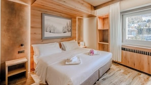 A modern bedroom with a large bed, a window with a city view, and a framed picture on the wall. - Hotiday Sauze Torre (Sauze d'Oulx)
