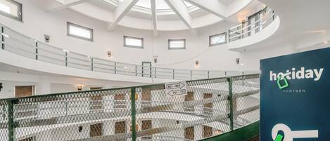 A spacious atrium with a high ceiling and skylights, a green safety railing, and a sign indicating 'hotday partner'.