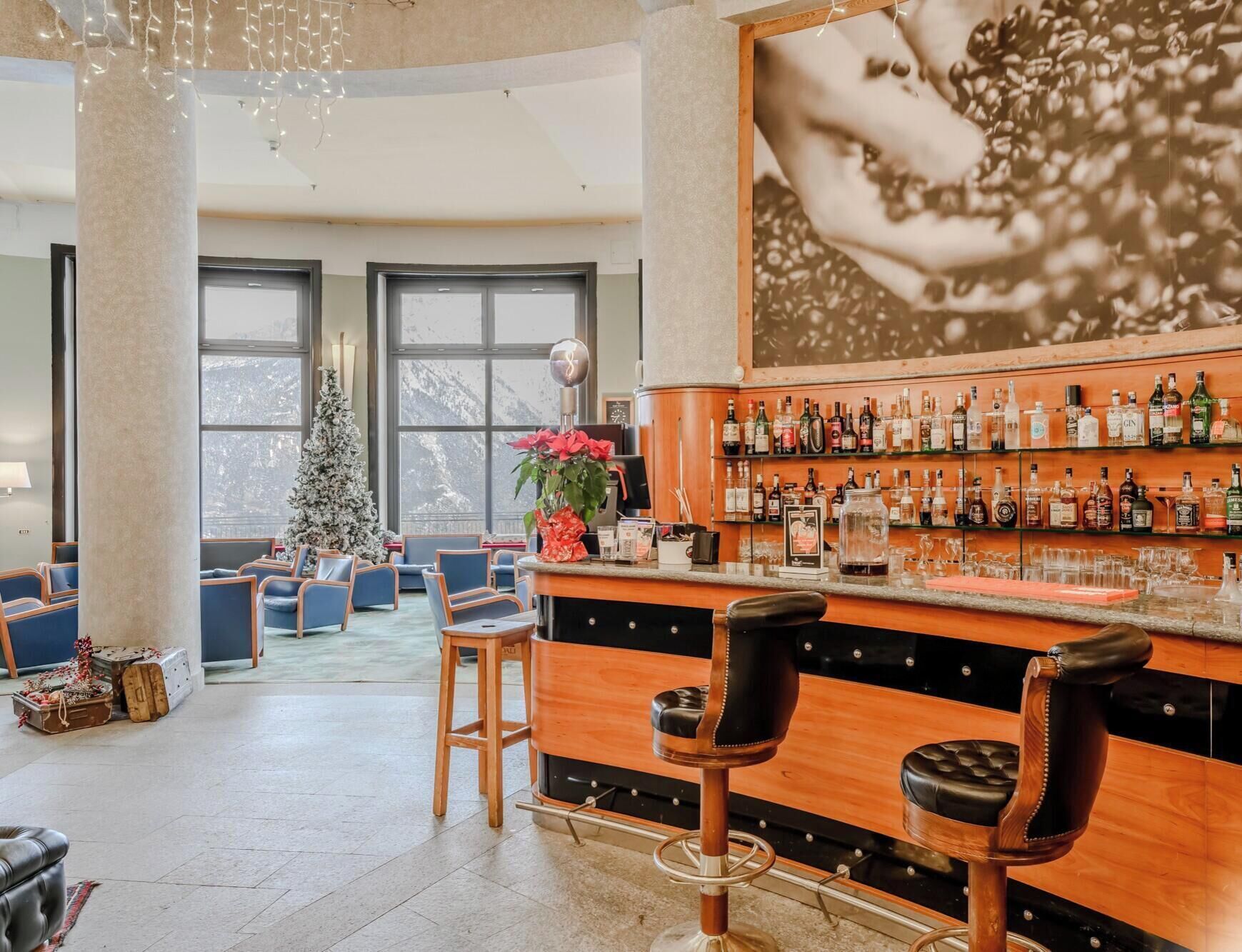 A bar area with a wooden counter, multiple stools, and a Christmas tree.
