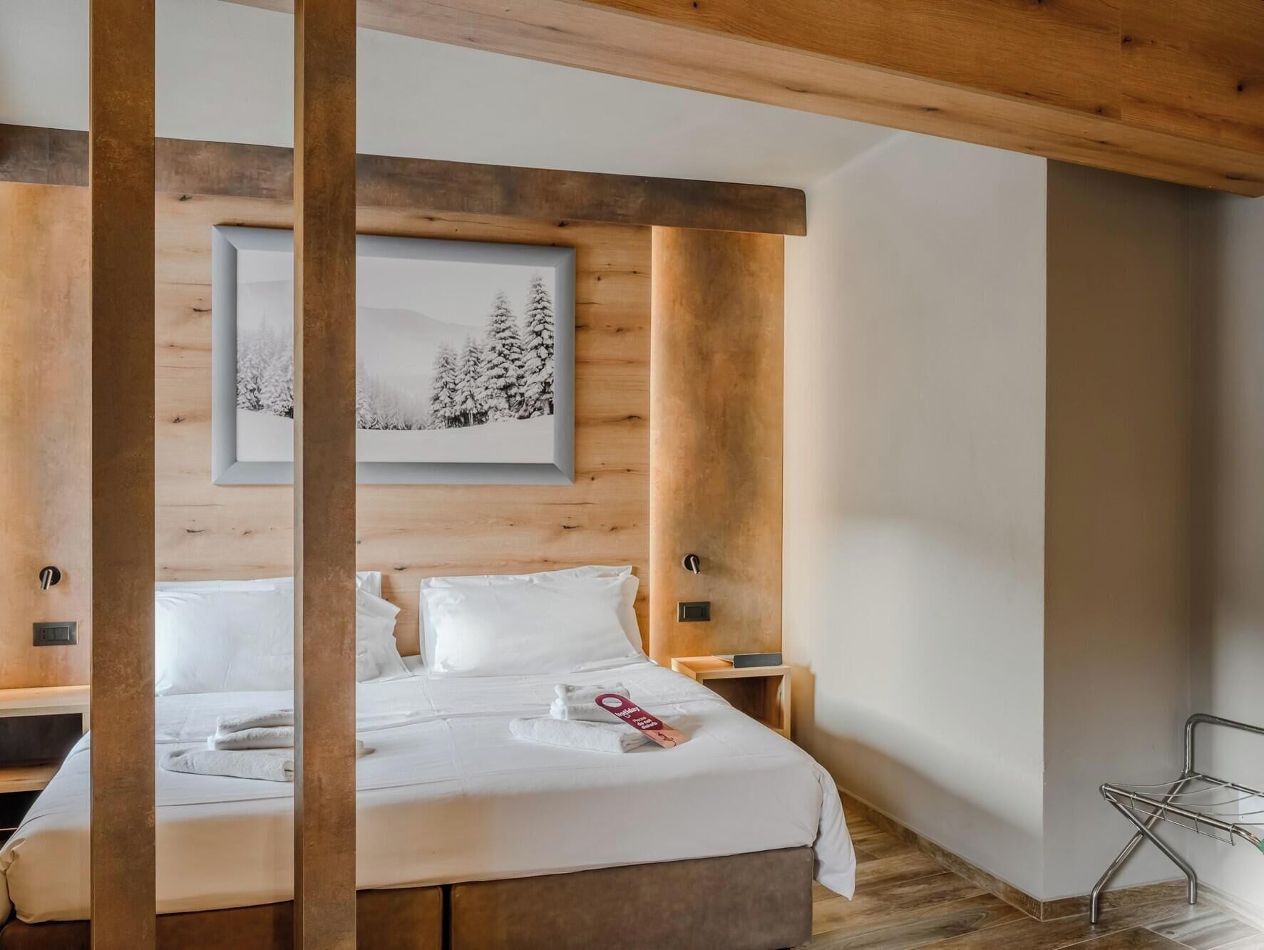 A hotel room with a bed, a framed picture on the wall, and a wooden ceiling.