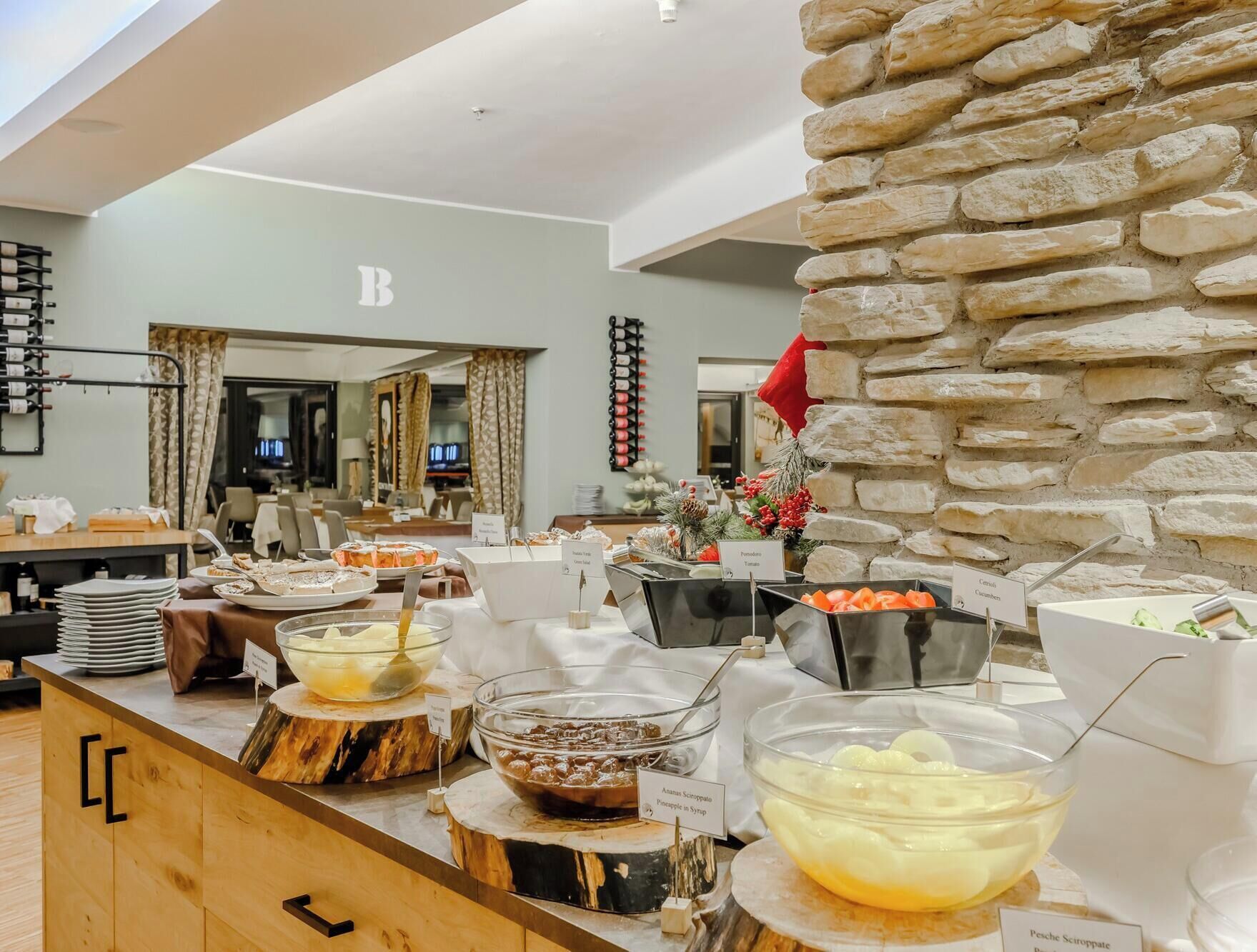 A buffet setup with various food items and a stone wall.