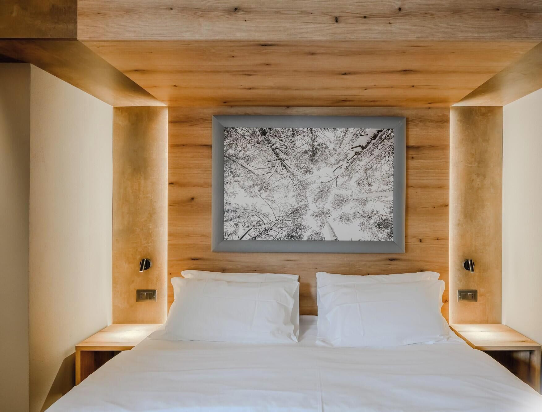 Ein Schlafzimmer mit einem Bett, zwei Nachttischen, einem gerahmten Bild an der Wand und Holzvertäfelung an der Decke.
