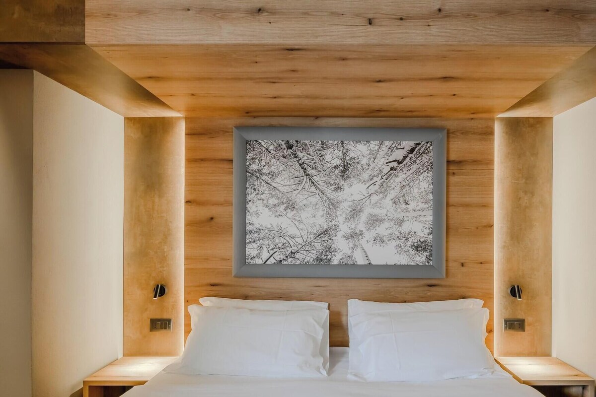 Un dormitorio moderno con una cama grande, dos mesitas de noche y una obra de arte abstracta colgada en la pared.