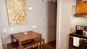 A kitchen with a wooden table and bench, a stove, and a painting on the wall. - New!Quaint & Convenient Hideaway: Great Location (East Hartford)