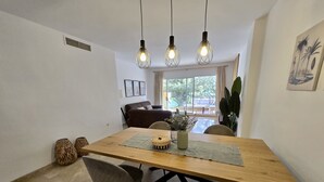 Un'area pranzo con un tavolo in legno, due sedie, un vaso con fiori e lampade a sospensione.