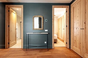Stylish hallway with a central console table and mirror, flanked by wooden doors leading to other rooms.