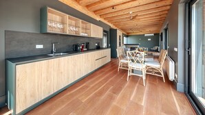 Une cuisine moderne avec des meubles en bois, un îlot central et un coin repas doté de chaises en osier.