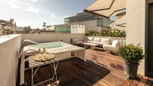 Une terrasse sur le toit équipée d’un jacuzzi, de chaises longues et d’une plante en pot.