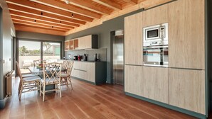 Une cuisine moderne avec des meubles en bois, un coin repas avec une table et des chaises, et une vue par la fenêtre.