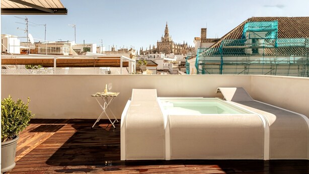 Une terrasse sur le toit avec un jacuzzi, une petite table et une plante en pot.