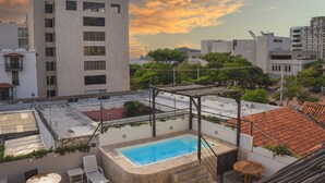 A rooftop pool with a pergola, surrounded by greenery and overlooking a cityscape. - Hotel Puerto Pelicano (Santa Marta)