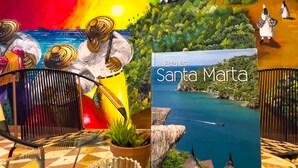 A room with a colorful mural, a framed picture of Santa Marta, a glass bowl with decorative items, and a chair. - Hotel Puerto Pelicano (Santa Marta)