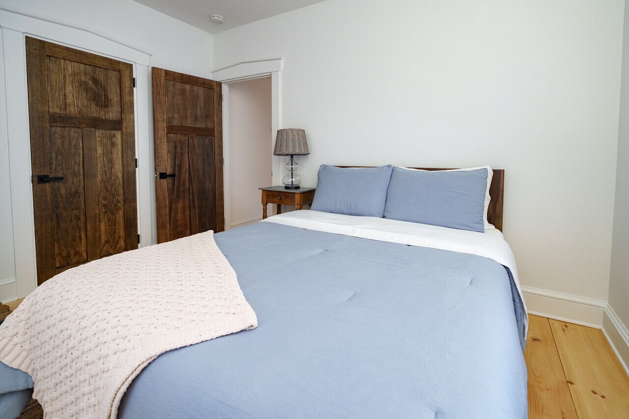 Une chambre à coucher avec un grand lit, une table de chevet avec une lampe et deux portes en bois.