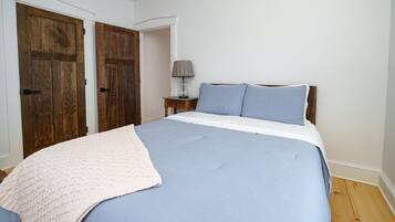 Une chambre à coucher avec un grand lit, une table de chevet avec une lampe et deux portes en bois.