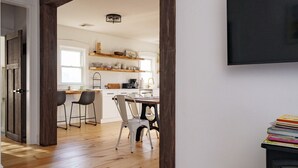 Uma cozinha moderna com piso de madeira, armários brancos e um espaço de refeições com duas cadeiras.