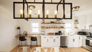Uma cozinha moderna com armários brancos, bancada de madeira e um espaço de refeições com mesa e cadeiras.