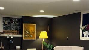 Un salon avec deux fauteuils, une table basse, une lampe et un tableau au mur.