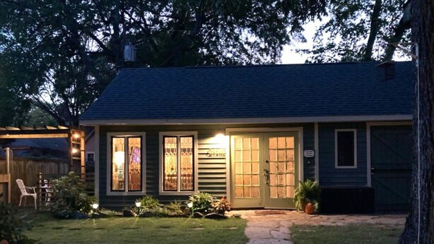 A small house with a dark roof, a front porch, and a covered patio area. - Tiny House Cottage in Historic Downtown (Little Rock)