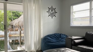Un soggiorno moderno con una grande finestra, un sacco di fagioli blu, un divano in pelle e una decorazione murale a tema nautico.