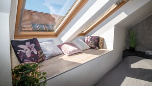 A skylight with a view of a brick building, a bench with cushions, and a potted plant. - Palms Apartments Budapest (Budapest)