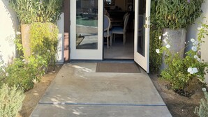 A house entrance with a sliding glass door, a concrete pathway, and a dining area visible through the door. - 1/2acre Adult & Kid Playground-relax & have fun! Pool/spa-golf-tennis-shopping (La Quinta)