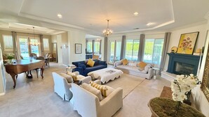 A spacious living room with a dining area, a fireplace, and large windows. - 1/2acre Adult & Kid Playground-relax & have fun! Pool/spa-golf-tennis-shopping (La Quinta)