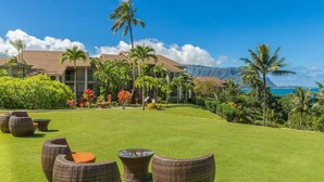 A resort with a well-maintained lawn, wicker furniture, and a view of the ocean and mountains. - Hanalei Bay Resort-A/C, Beach, Bali Hai Views from 3 Lanai's, Washer & Dryer (Princeville)