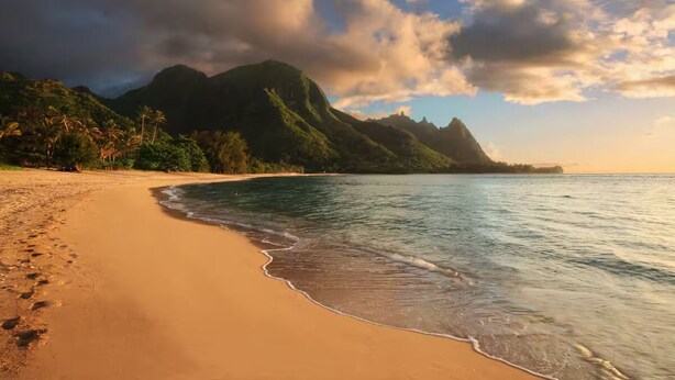 A beach with clear waters, a sandy shore, and a mountain in the background. - Hanalei Bay Resort-A/C, Beach, Bali Hai Views from 3 Lanai's, Washer & Dryer (Princeville)