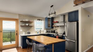 Una cocina moderna con una isla grande, taburetes de bar, horno empotrado y refrigerador.