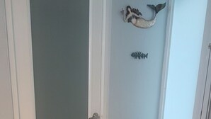 A hallway with a closed door, a small cabinet with drawers, and wall decorations including a fish and a starfish. - Walk to beach & Kioskos, close to rainforest, cold air, free parking  (Luquillo)