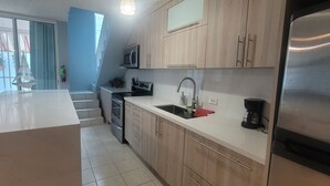 A modern kitchen with wooden cabinets, a stainless steel refrigerator, a microwave, and a coffee maker. - Walk to beach & Kioskos, close to rainforest, cold air, free parking  (Luquillo)