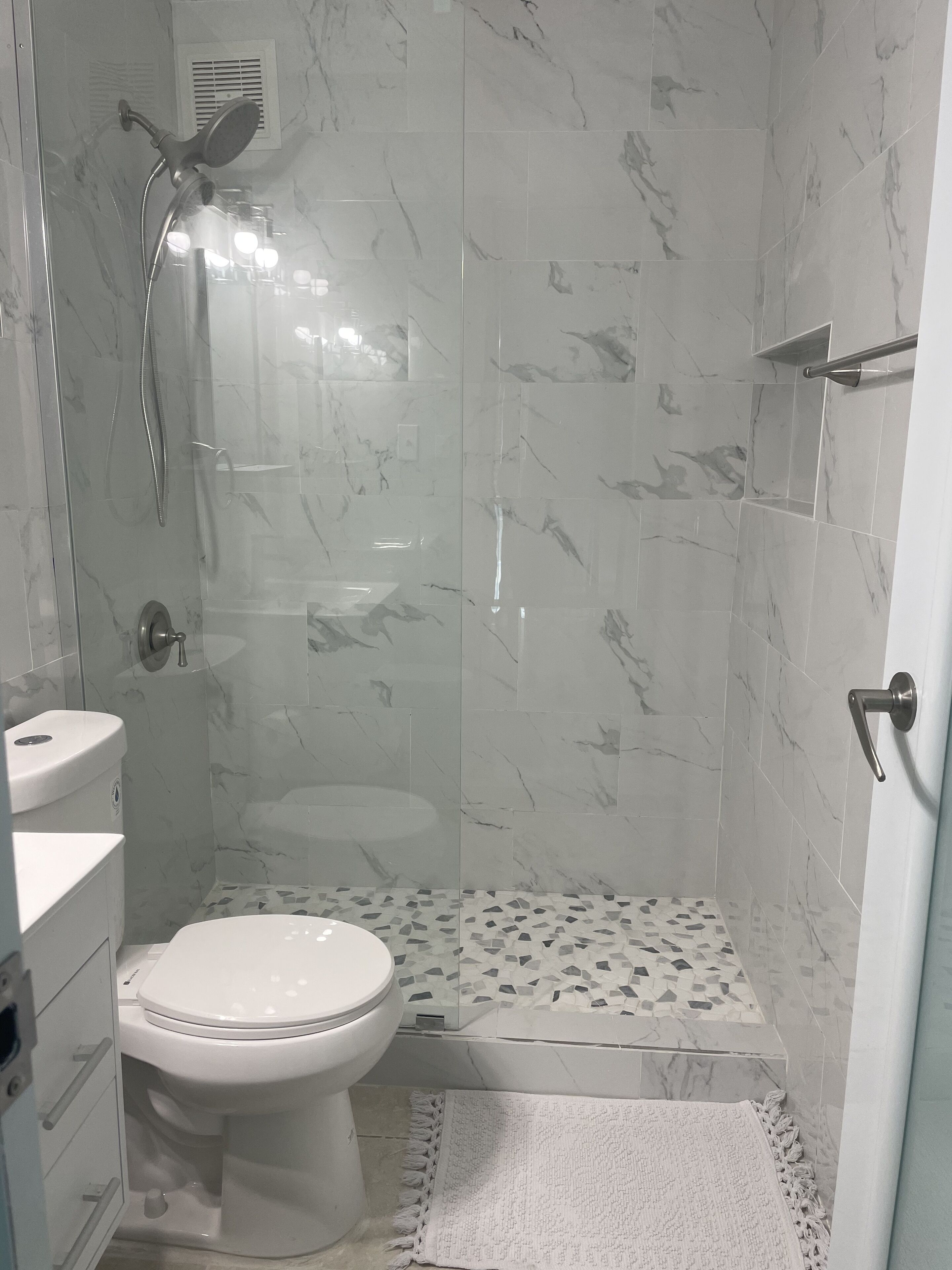 A bathroom with a toilet, shower, and sink.
