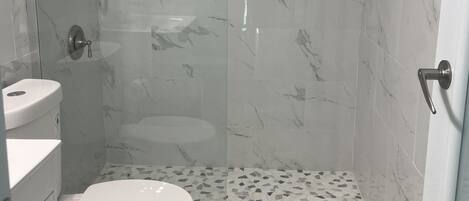 A bathroom with a toilet, shower, and sink.