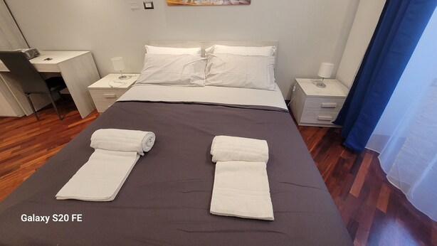 A hotel room with a bed, a desk, a chair, two nightstands, and a painting of the Colosseum. - 5 minutes walk from saint peter vatican museums castel sant angelo. At 50m meter (Roma)